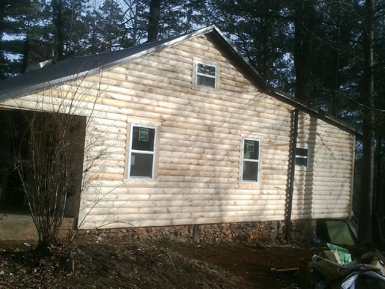 New log siding and dark metal roofing on a gable end in Groveton