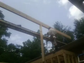 Carpenter setting a ridge beam over a new addition frame — Ice Dam Removal by Roofing Brothers in Groveton