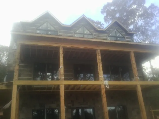 Dormers and porch framing on a large log home under construction — Roof Coating work by our crew in Groveton