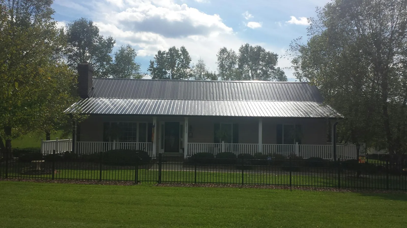 Gray metal roof on a brick ranch with a full width front porch — Gutter Guard Installation work by our crew in Groveton