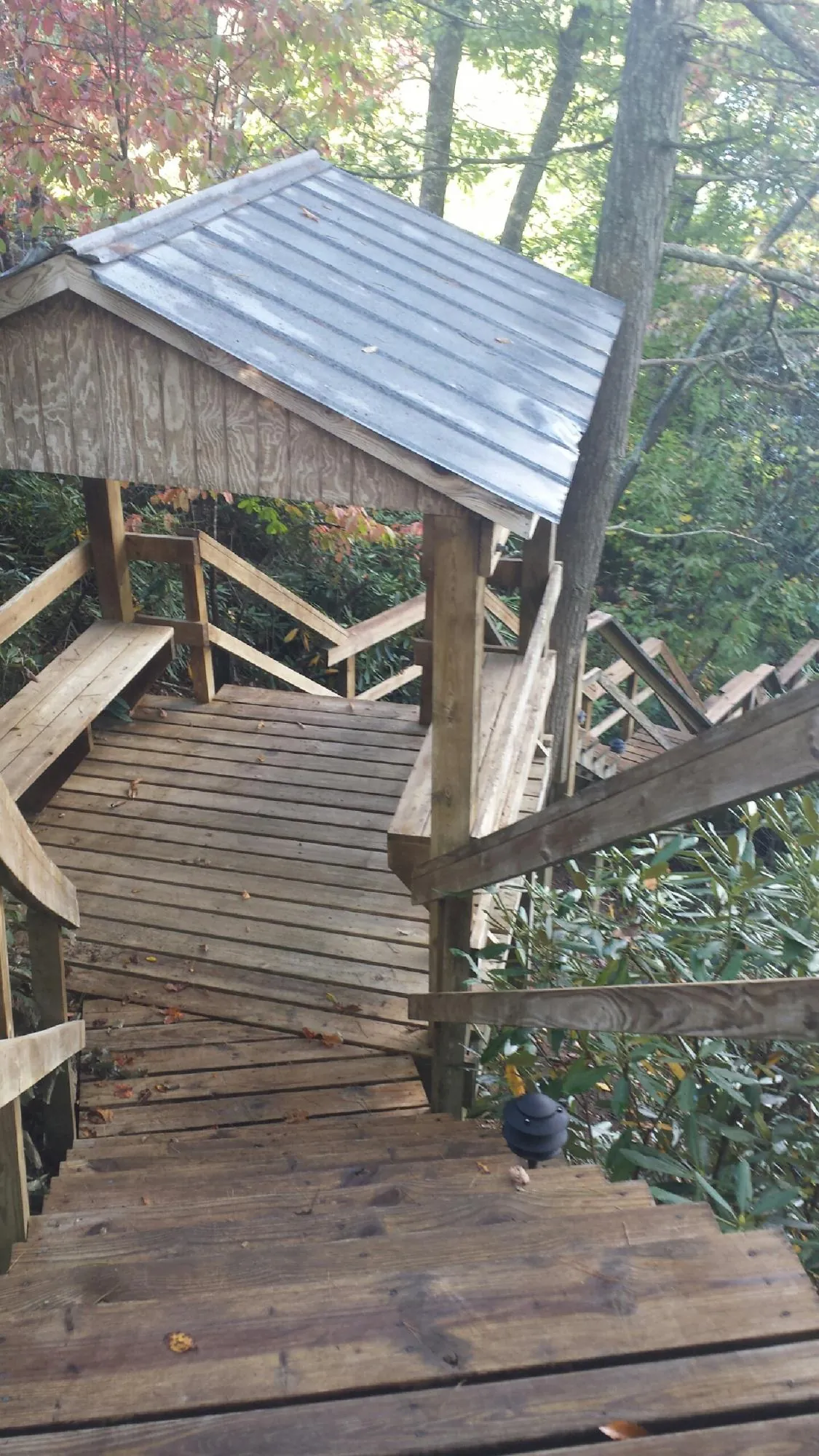 Metal roofed shelter over wooden steps on a wooded walkway — Skylight Repair & Installation work by our crew in Groveton