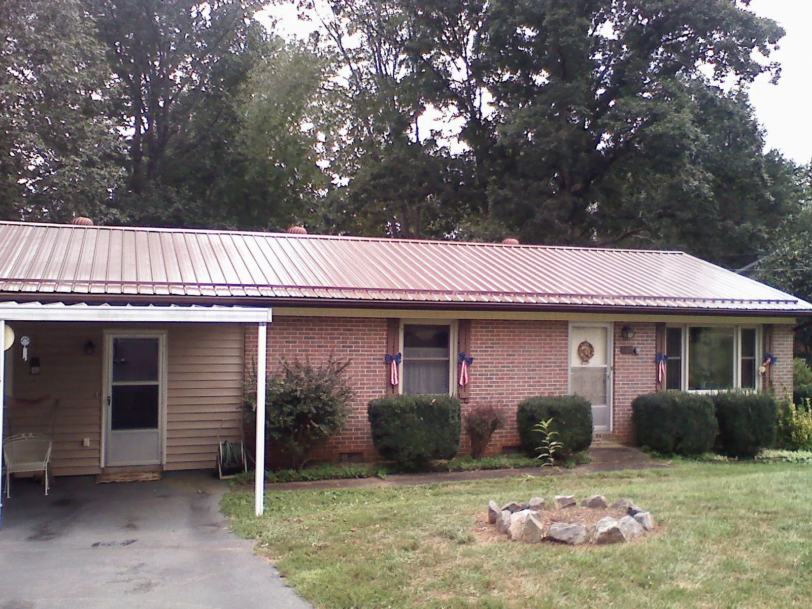 Bronze metal roof and carport on a brick ranch home — Roof Repair work by our crew in Groveton